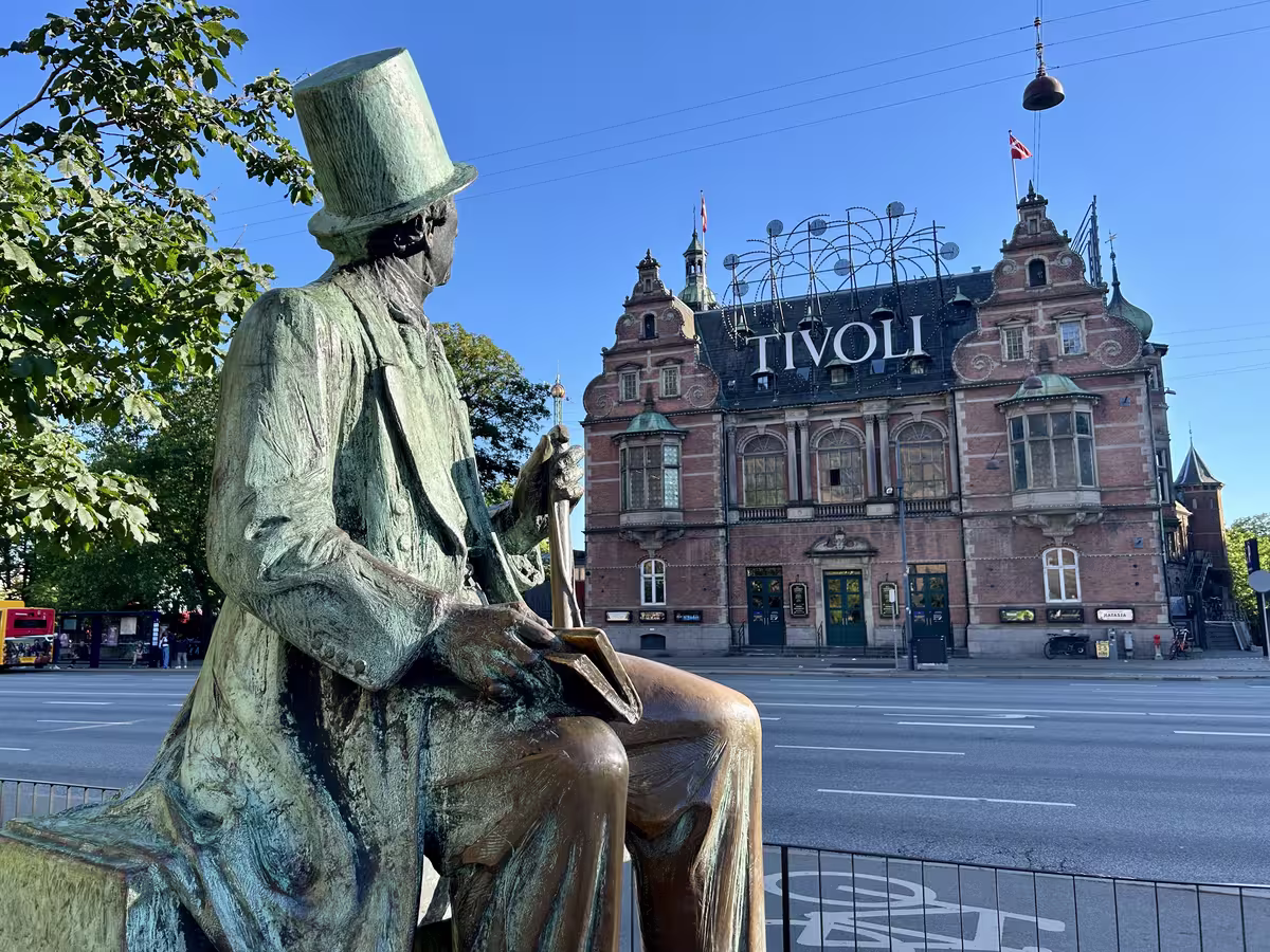 这座著名的安徒生雕像（Hans Christian Andersen Statue）静静伫立在哥本哈根市政厅旁，他正深情凝望街对面那座始建于1843年、曾带给他无限童话灵感的趣伏里公园（Tivoli Gardens），成为了丹麦哥本哈根最经典且必游的文化地标组合。