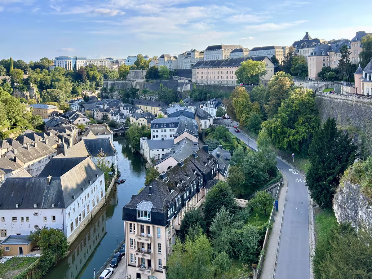 从“欧洲最美阳台”（Chemin de la Corniche）俯瞰，卢森堡市（Luxembourg City）老城核心的格伦德区（Grund）静卧于阿尔泽特河谷，历史建筑与河流交相辉映，是卢森堡旅游必打卡的经典机位。