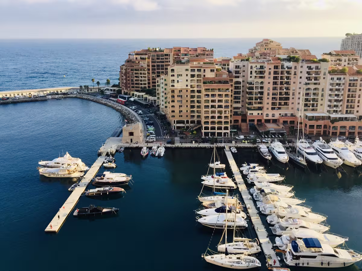 摩纳哥著名的丰维耶港区 (Port of Fontvieille)，以停泊在码头的各类游艇、沿海湾而建的豪华高层住宅建筑，以及远处的蔚蓝地中海景色为特色。