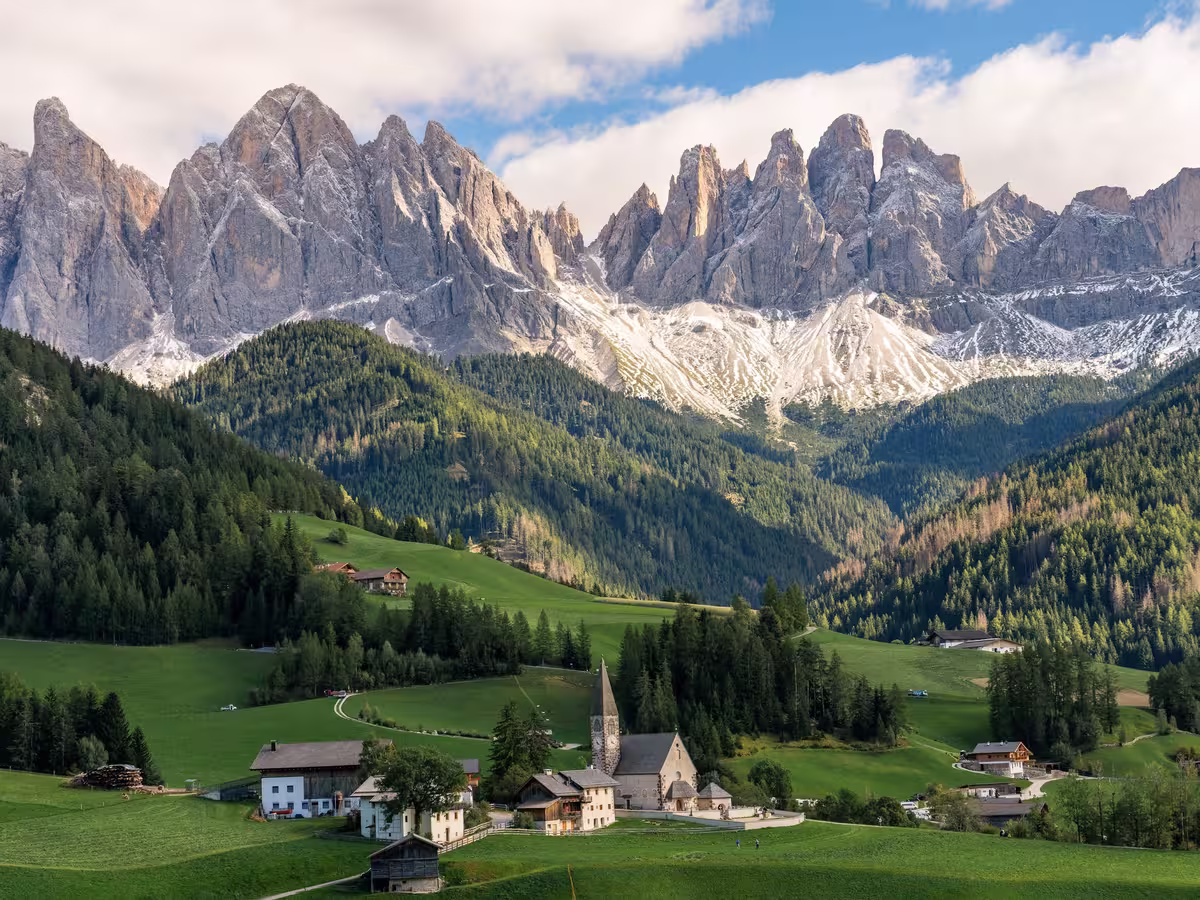 多洛米蒂 (Dolomites) 的富内斯山谷 (Val di Funes)。坐落在绿茵草坡上的是圣玛格达莱纳教堂 (Chiesa di Santa Maddalena)，远处是盖斯勒群峰 (Odle / Geisler Group)。
